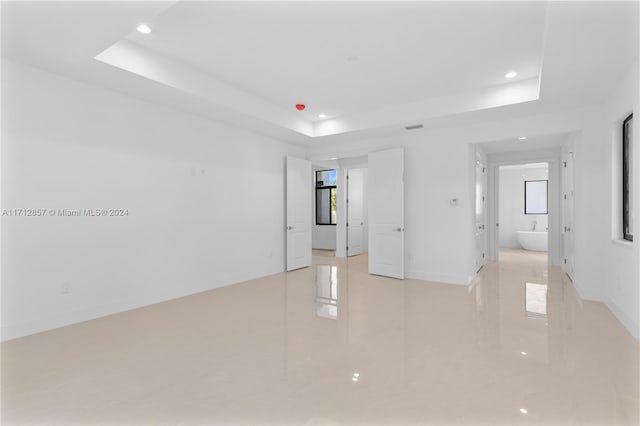 empty room featuring a tray ceiling and light tile patterned floors