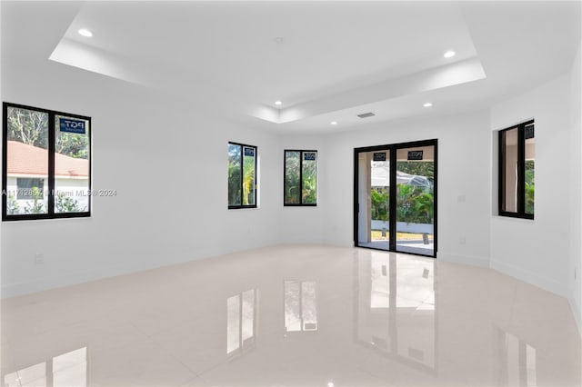 tiled spare room with a raised ceiling