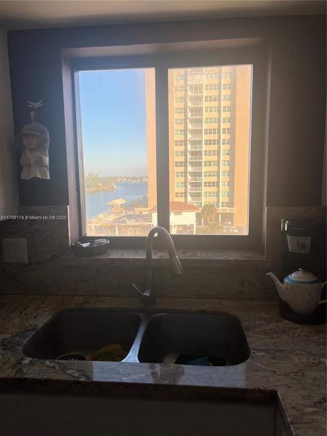 kitchen with a water view, stone countertops, and sink