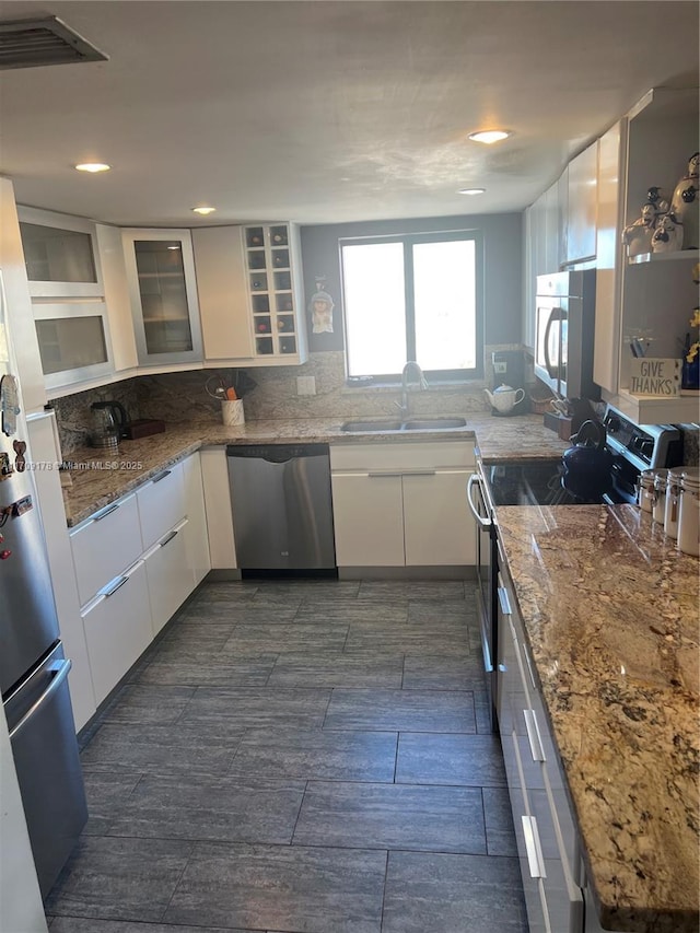 kitchen featuring white cabinetry, stainless steel appliances, sink, and stone counters