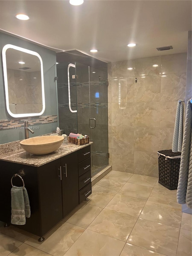 bathroom featuring vanity, tile walls, and walk in shower