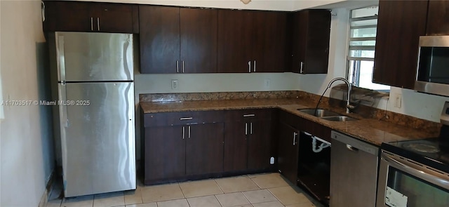 kitchen featuring dark stone counters, sink, light tile patterned floors, appliances with stainless steel finishes, and dark brown cabinetry