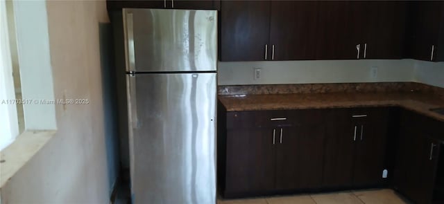 kitchen featuring dark brown cabinets, stainless steel refrigerator, and light tile patterned flooring