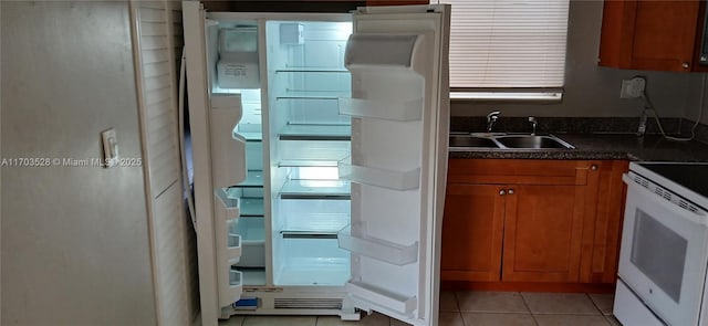 kitchen with refrigerator, light tile patterned floors, sink, and range