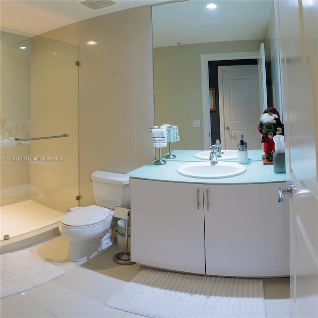 bathroom with tile walls, tile patterned flooring, vanity, toilet, and a shower with door