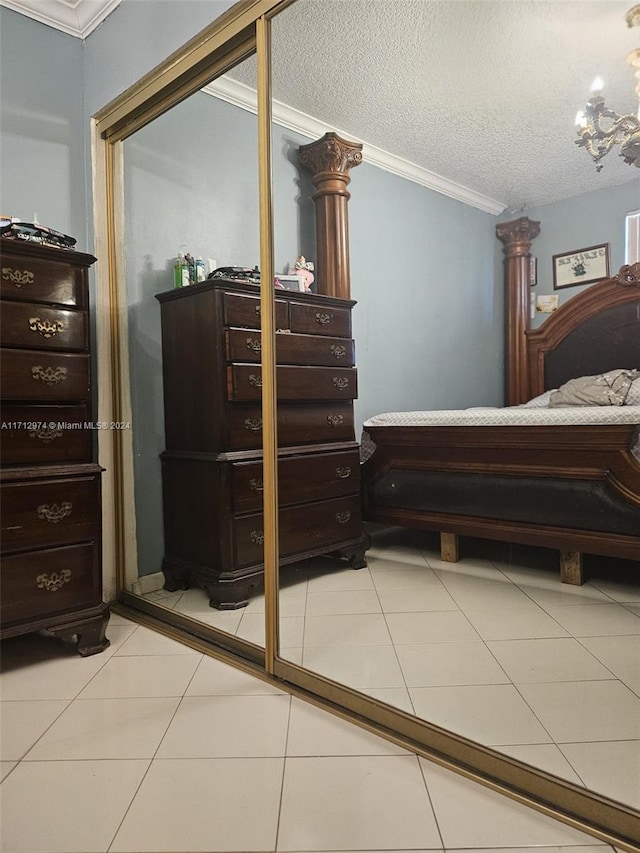 bedroom featuring tile patterned floors, ornate columns, a textured ceiling, and ornamental molding