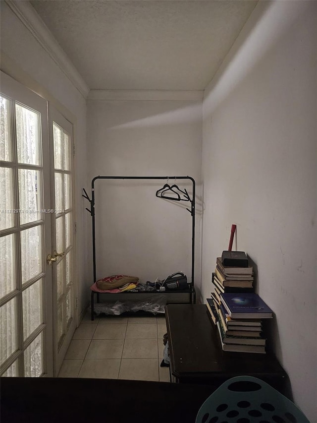 workout area featuring light tile patterned floors, a textured ceiling, french doors, and ornamental molding