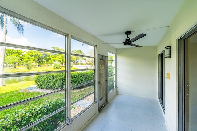 sunroom featuring ceiling fan and a water view