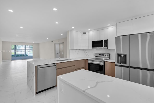 kitchen featuring appliances with stainless steel finishes, tasteful backsplash, light stone counters, sink, and white cabinetry