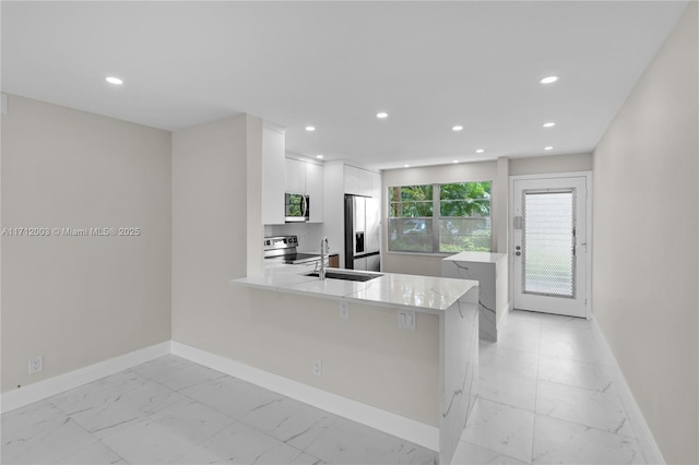 kitchen featuring kitchen peninsula, stainless steel appliances, white cabinets, and sink