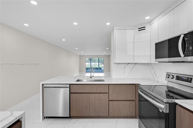 kitchen with white cabinetry, sink, light stone countertops, and appliances with stainless steel finishes