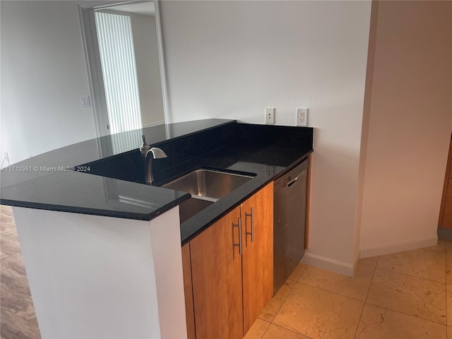 kitchen featuring dark stone countertops, dishwasher, and sink