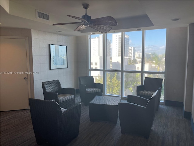 living room with dark wood-type flooring, ceiling fan, and a healthy amount of sunlight