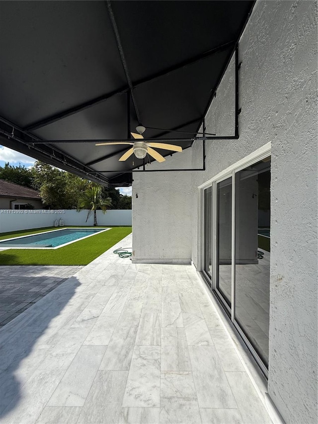 view of patio with ceiling fan and a pool