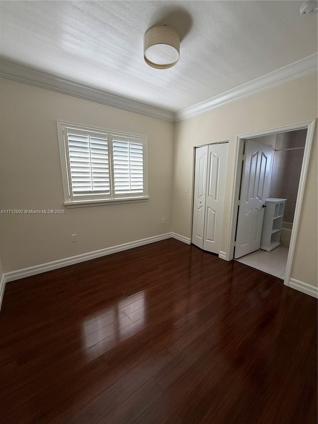 unfurnished bedroom featuring multiple closets, crown molding, and dark hardwood / wood-style floors