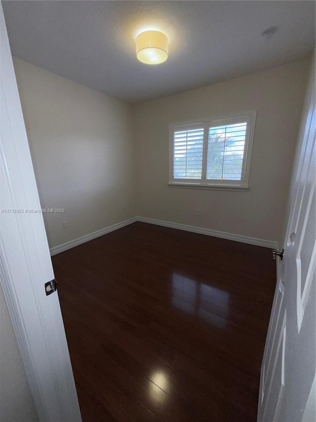 unfurnished room with dark wood-type flooring