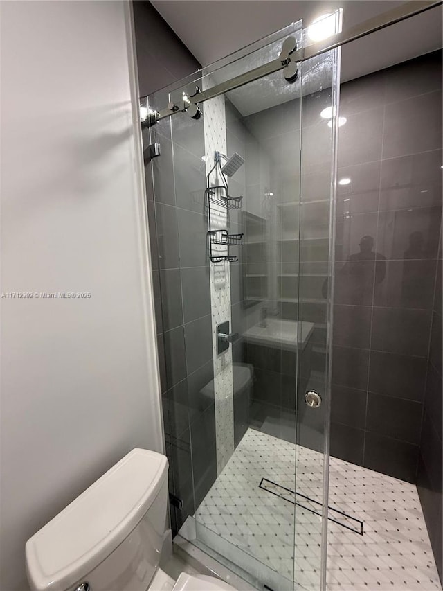 bathroom with toilet and a shower with shower door