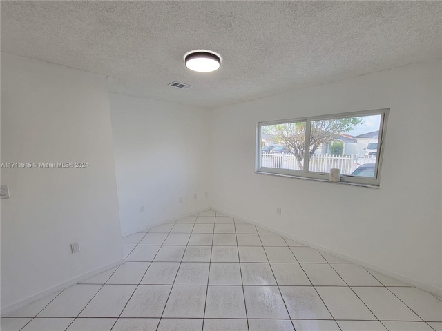 tiled empty room with a textured ceiling