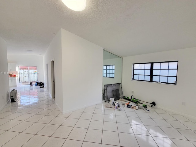 empty room featuring light tile patterned flooring, a textured ceiling, and a wealth of natural light