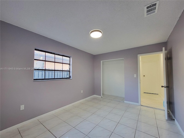 tiled empty room with a textured ceiling