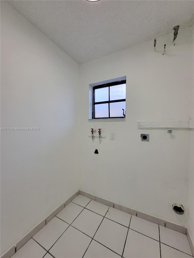 laundry area featuring hookup for an electric dryer, hookup for a washing machine, a textured ceiling, and light tile patterned floors