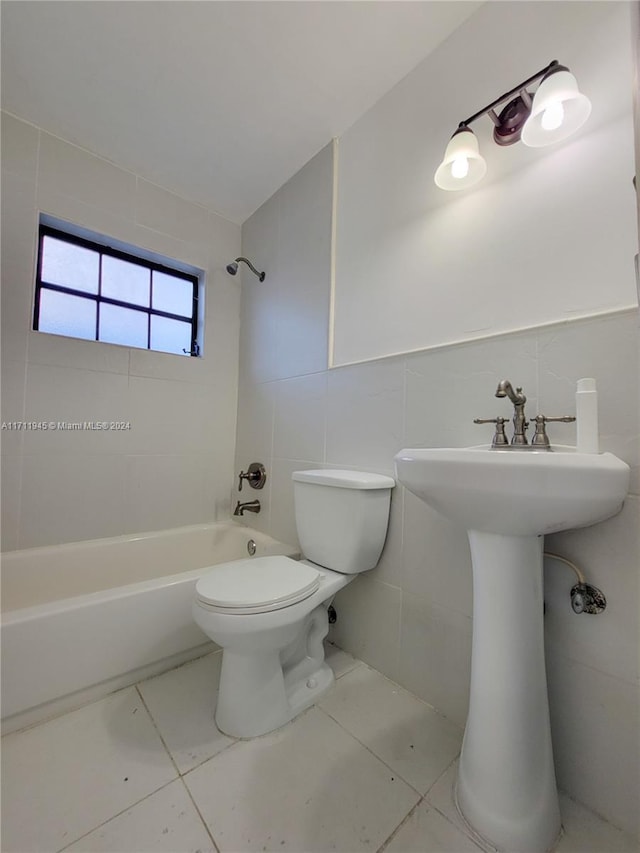 full bathroom with sink, tiled shower / bath combo, toilet, and tile walls