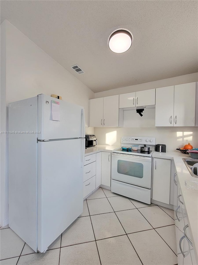 kitchen with sink, light tile patterned flooring, a textured ceiling, white appliances, and white cabinets