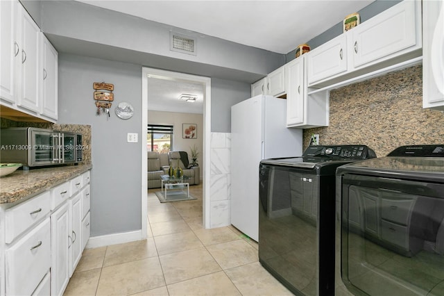 laundry area with washing machine and dryer, light tile patterned floors, and cabinets