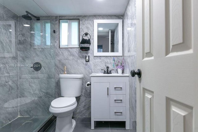 bathroom featuring vanity, toilet, tiled shower, and tile walls