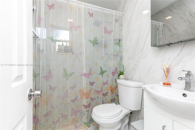 bathroom featuring vanity, toilet, tiled shower, and tile walls