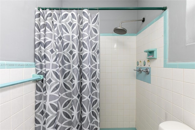 bathroom featuring curtained shower, tile walls, and toilet