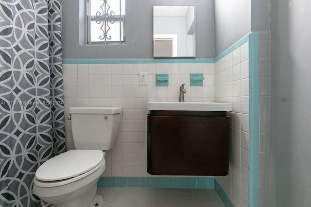 bathroom with walk in shower, vanity, tile walls, and toilet