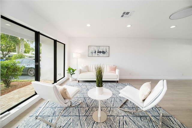 living room featuring light wood-type flooring, visible vents, baseboards, and recessed lighting