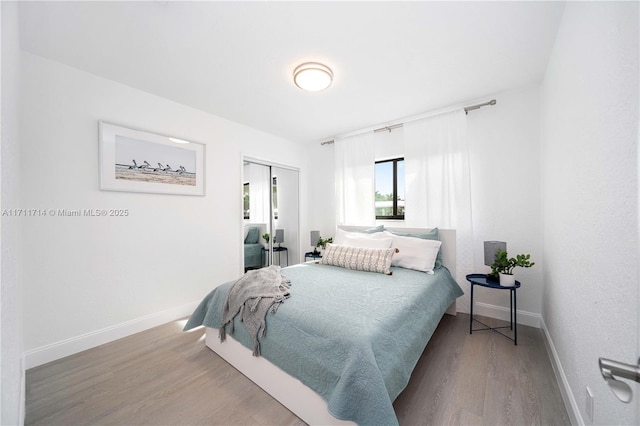 bedroom with a closet, baseboards, and wood finished floors