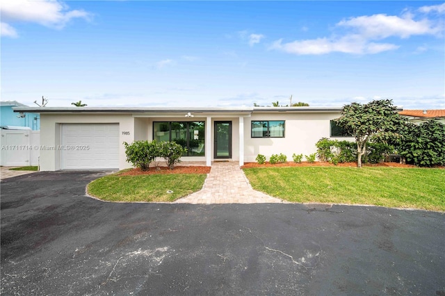 view of front of house with a front lawn, driveway, an attached garage, and stucco siding