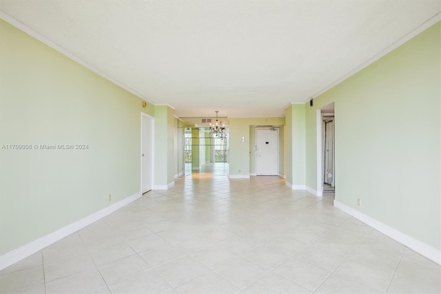 tiled empty room with crown molding and a chandelier