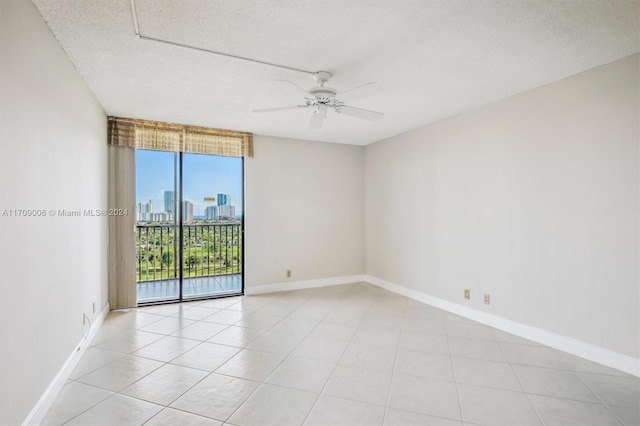 empty room featuring ceiling fan, light tile patterned floors, and a textured ceiling