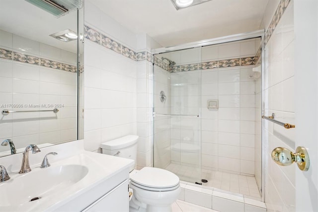 bathroom featuring a shower with door, vanity, tile walls, and toilet