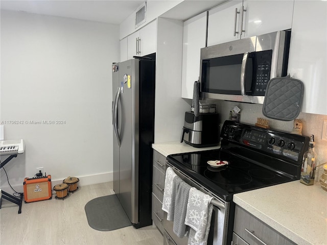 kitchen with light hardwood / wood-style flooring, white cabinets, and stainless steel appliances