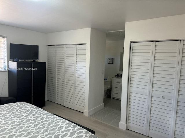 bedroom with connected bathroom and light hardwood / wood-style floors