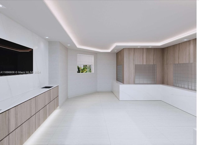 interior space featuring a tray ceiling and light tile patterned flooring