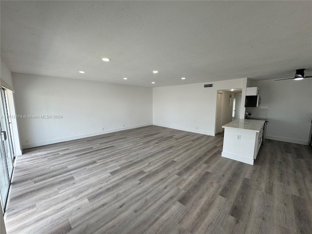 unfurnished living room with ceiling fan, a textured ceiling, and light wood-type flooring