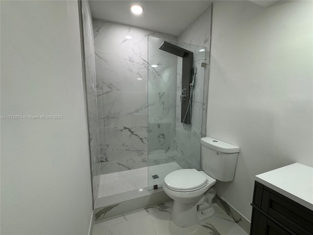 bathroom with tiled shower, vanity, and toilet