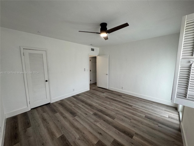 unfurnished bedroom with dark hardwood / wood-style flooring, a closet, and ceiling fan