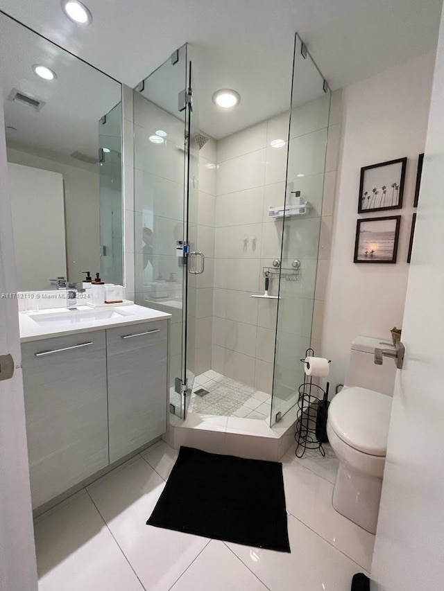 bathroom with tile patterned floors, vanity, toilet, and a shower with shower door