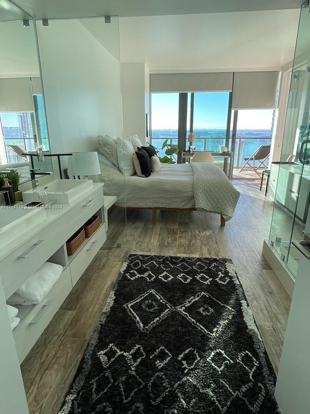 bedroom featuring access to outside, a water view, and hardwood / wood-style flooring