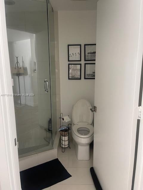 bathroom with tile patterned floors, toilet, and an enclosed shower