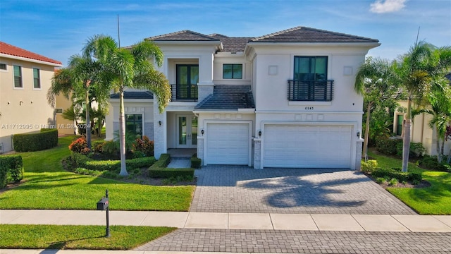 view of front of house with french doors, a balcony, a front yard, and a garage