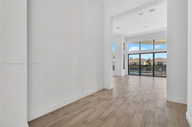 spare room featuring a towering ceiling and light wood-type flooring