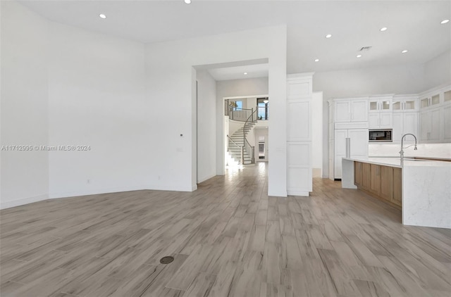 kitchen featuring white cabinets, light hardwood / wood-style floors, built in appliances, and sink